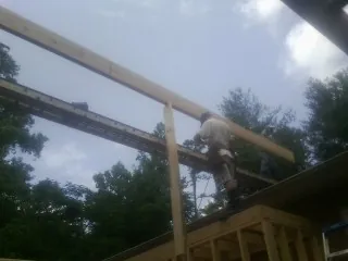 Carpenter setting a ridge beam over a new addition frame — Ice Dam Removal by Roofing Brothers in Howell